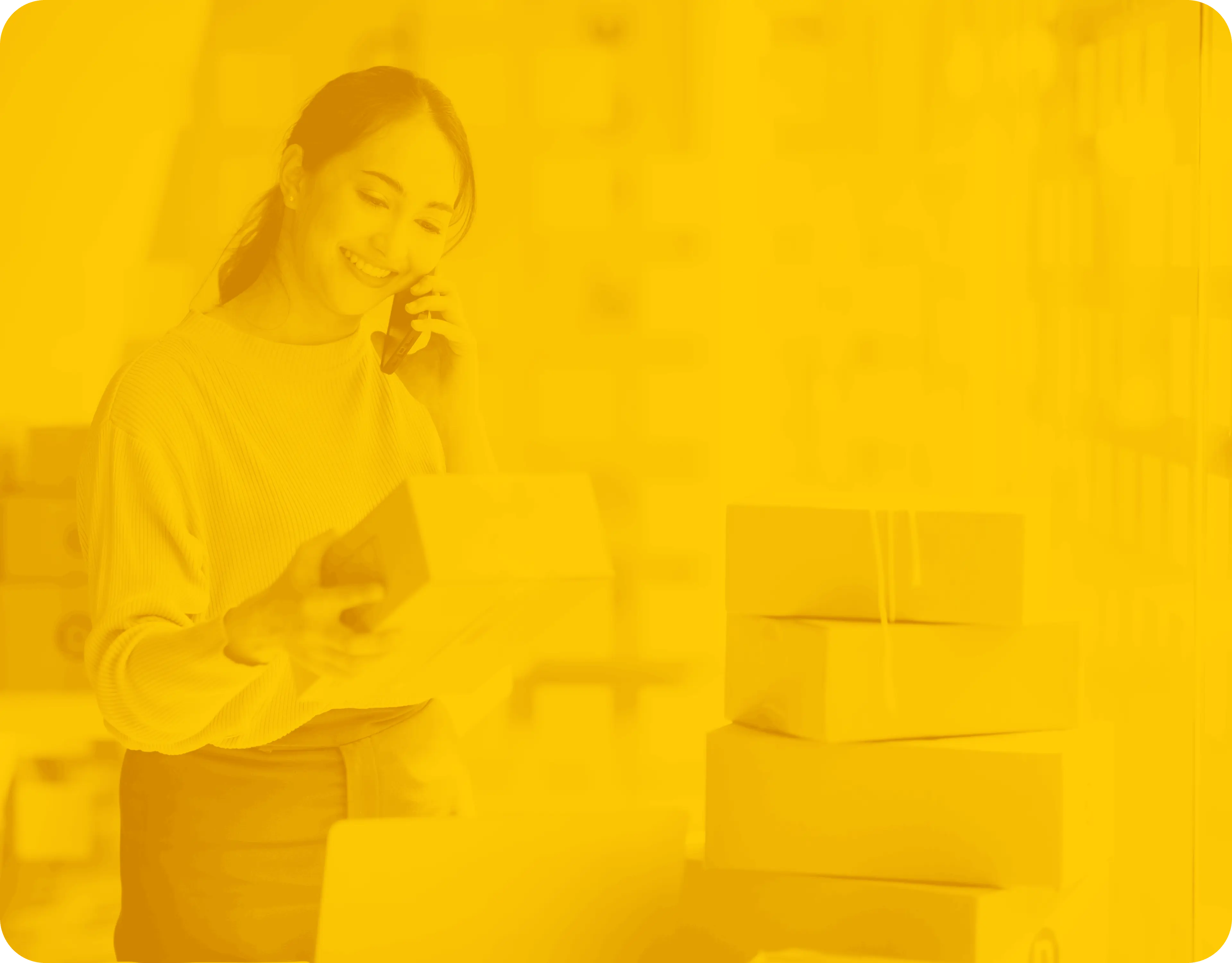 An image of a smiling young woman holding a phone to her ear, seemingly glad she received a gift with the box she's holding